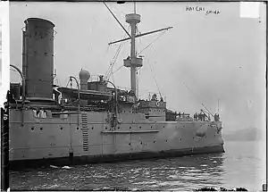 A black-and-white photograph of the bow of a ship entering the picture from the left. A number of crew members are visible on deck. The words "HAI CHI CHINA" are visible in the upper right-hand corner of the photo, along with what appears to be the imprint of a stamp.